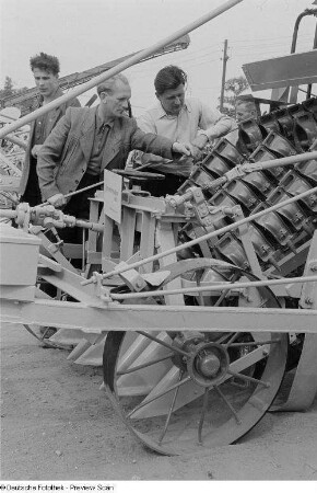 Ausstellungsbesucher an einem landwirtschaftlichen Gerät