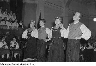Tanzende Paare in Tracht, Chor und Orchester des Pionierensembles "Julian Marchlewski" der Humboldtschule bei einer Kulturveranstaltung, im Hintergrund Zuschauer