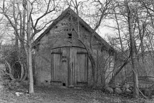 Gut Jersbek: Spritzenhaus aus Backstein: Giebelseite mit Tor, darüber Jahreszahl 1879: Bäume, Büsche, am Boden Feldsteine