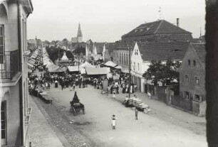 Radebeul-Kötzschenbroda, Altkötzschenbroda. Blick aus einem Wohnhaus nach Südosten über den Markt und Anger mit Markttreiben gegen den Turm der Friedenskirche