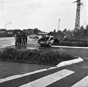 Verkehrsunfall: Kreuzung Industriestraße mit Ratzeburger Straße: Zusammenstoß von zwei Pkws: ein Unfallwagen mit eingedrückter Karosserie, geöffneten Türen und offener Heckklappe auf Verkehrsinsel, an verbogenem Straßenschild "Industriestraße" und verbogenem Wegweiser nach Kiel und Hamburg: Polizist, Personen: hinten quer auf Ratzeburger Straße zweiter Unfallwagen mit eingedrückter Front: Lampenmasten, Hochspannungsmast: hinten links Lkw der Spedition Willy Schuldt, Firmengebäude: im Hintergrund Wohnhäuser: im Vordergrund Verkehrsinsel, Zebrastreifen