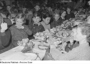 Mütter und beschenkte Kinder an einer geschmückten Tafel bei der Weihnachtsfeier des Verlags Volk und Wissen