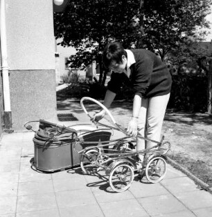 Frau beim Zusammenklappen eines Kinderwagengestelles