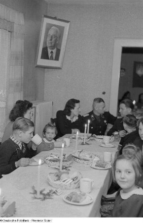 Kinder und Erwachsene am gedeckten Tisch sitzend