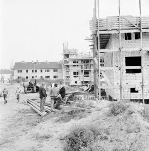 Wohnungsbau: Wohngebiet Kellerberg-Süd: Wohnblocks im Bau: Rohbauten der Neuen Lübeck-Südholsteinischen Baugenossenschaft, teilweise mit Gerüsten: links Anhänger mit Brettern: Arbeiter beim Entladen