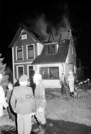 Brand: Zweifamilienhaus: vorn Feuerwehrmänner: hinten Mitte Brandruine: Nacht