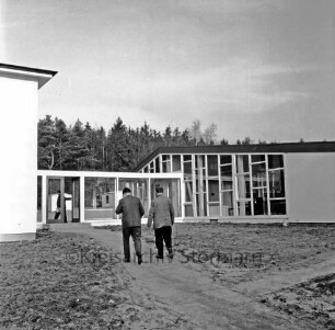 Franz-Spliedt-Heim: Jugendheim des Deutschen Gewerkschaftsbundes (DGB-Nordmark): Seebergen: Erweiterungsbau mit Lehrsaal und Bettenhaus vor Fertigstellung: vorn unbefestigte Außenanlagen: zwei Männer auf dem Weg ins Gebäude