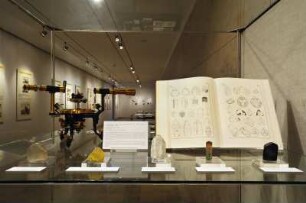 SLUB, Ausstellung "Gespräche mit der Erde. Geowissenschaften in Sachsen" : Ausstellungspräsentation im Buchmuseum. Hochvitrine mit Mineralien, Atlas der Krystallformen von Victor Goldschmidt, 1923 (Tafel 18 und 19: Turmalin) und Reflexionsgoniometer