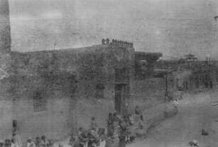 Menschenmenge vor einem Gebäude : Eine Menschenmenge vor einem Lehmgebäude, möglicherweise eine Moschee, in einer zentralasiatischen Stadt im Tian Shan Hochgebirge
