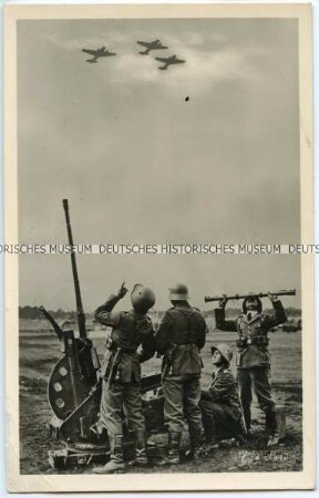 Wehrmachtssoldaten an einer Flugabwehrkanone beobachten Flugzeuge