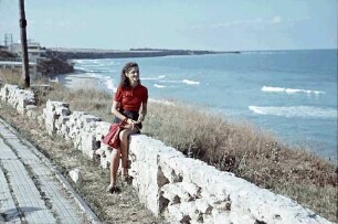 Eforie: Schwarzmeer Strand, Margarete Klein sitzt auf Steinzaun, Hintergrund Küste