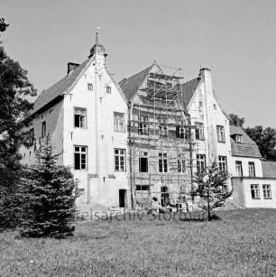 Kloster Nütschau: Herrenhaus: Restaurierung der Südfront: Gerüst vor Mittelflügel: davor Baumaterial: vorn Rasenfläche: rechts und links Bäume