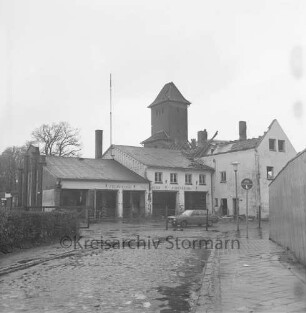 Feuerwache Woldenhorn: Schäferweg: [ehemaliges Elektrizitätswerk]: Abriss: Verwaltungsgebäude ohne Dachstuhl: Feuerwehrgerätehaus mit Funkantenne: dahinter Schlauchturm: davor Pkw, Bauzaun, Straßenlampe, Verkehrsschild