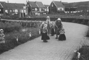 Meisjes auf Klinkerstrasse : Eine Gruppe von Mädchen auf einer Kopfsteinpflasterstraße. Im Hintergrund Holzhäuser