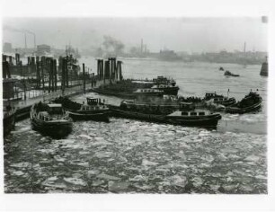 Hamburg-Mitte. Winter. Schichtwechsel am Baumwall. Hafen- und Werftarbeiter auf dem Weg zu ihren Arbeitsstellen. Sie werden von Fähren und Barkassen durch das teilweise vereiste Hafenbecken transportiert