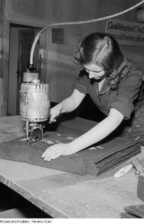 Portrait einer Frau beim industriellen Zuschneiden von Stoff im VEB Bekleidungswerk Leipzig