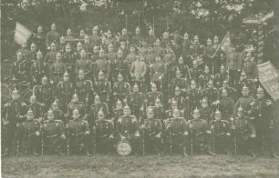 9. Kompanie (ca. achtzig Personen) des Regiments bei Verabschiedung des Kompanieführers Ludwig von Breuning (1870-1940), Leutnant, zuletzt Oberstleutnant ,im Freien mit Gewehren und Fahnen, teils stehend oder kniend