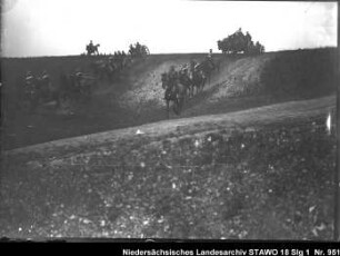 Besichtigung des Feld-Artillerie-Regiments Nr. 46 Enthält: Soldaten zu Pferd und auf mit Pferden bespannten Geschützlafetten reiten einen Hang hinunter