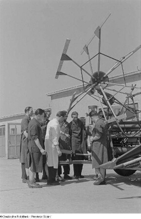 Angehörige der Fachschule für Landwirtschaftsmaschinenbau beim Unterricht, vor einem Mähdrescher