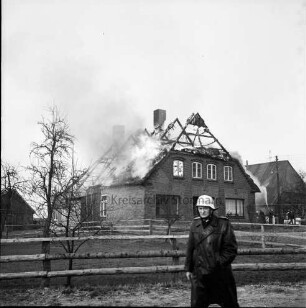 Brand: Reetdachhaus auf Nachbarhof Holm: Funkenflug vom Brand des Hofes von Walter Ellerbrock: brennendes Dach: links Feuerwehrleute beim Löschen: im Vordergrund Feuerwehrmann