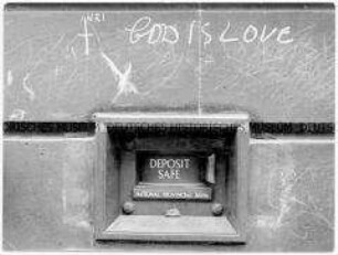 Banksafe in einer Hauswand, darüber die Inschrift "God is love"