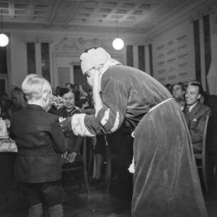 Der Weihnachtsmann übergibt einem Jungen Geschenke, Kinderfest zur Weihnachtszeit