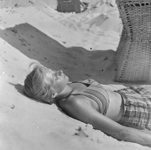 Frau liegt am Strand