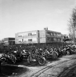 Schulzentrum Am Heimgarten: Reesenbüttler Redder: Außenaufnahme: vorne Parkplatz, abgestellte Motorräder und Mopeds