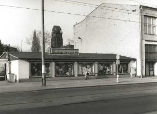 Dresden-Löbtau. Kaufhaus "Konsument", Kesselsdorfer Straße 22. Straßenansicht des linken Flachbaues mit Turm der Friedenskirche dahinter