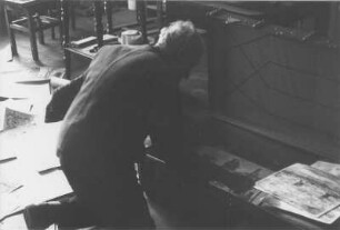 Dresden-Bühlau, Kirschauer Straße 8. Der Maler Wilhelm Rudolph (1889-1982) in seinem Atelier beim Betrachten von in einem Reisekoffer liegenden Zeichnungen (wohl Zyklus "Das zerstörte Dresden)