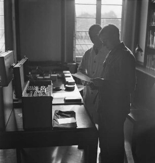 Carl Albiker und Wolfgang Pfeiffer kontrollieren Listen und Kästen im Lesesaal des Kunstgeschichtlichen Seminars der Marburger Universität im Rahmen der Vorbereitungen für die Fotokampagne im besetzten Frankreich