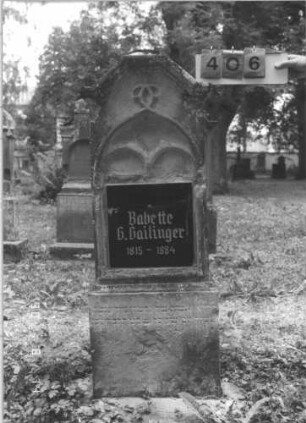 Grabstein 406 (Index: 99787637) Material: Sandstein und schwarze Glasplatte Zustand: sehr stark verwittert, später eingesetzte Texttafel zerbrochen und repariert Maße HxBxT: 134x47x17 cm Besonderheit: Schrift grau: Grabstein 406