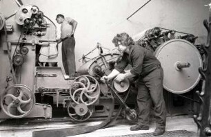 Papiermaschine : Zwei Arbeiter bei der Einstellung und Reparierung einer Papierfördermaschine