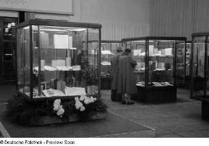 Besucher betrachten die in Vitrinen ausgestellten Exponate bei der 2. Deutschen Buchkunst-Ausstellung