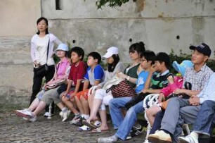 Chinesische Touristen : Chinesische Touristen sitzen im Innenhof des Strahov-Klosters auf einer Bank. Aufgenommen in Prag am 31. Juli 2009
