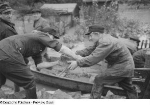 Männer bei Schutzvorkehrungen (Stabilisieren eines Dammes mit Steinen)
