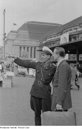 Polizist weist einem Händler am Hauptbahnhof den Weg
