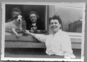 Etha Richter mit zwei Frauen und Hund, aus einem Fenster schauend