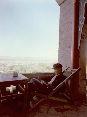 Lesender Mann in einem auf einer Terrasse stehenden Liegestuhl