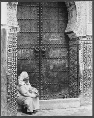 Portal einer Moschee : Eine verschleierte Frau sitzt vor dem Eingang einer Moschee in der marokkanischen Stadt Fès