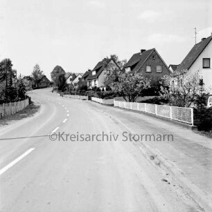 Straße: rechts und hinten Einfamilienhäuser mit Vorgärten