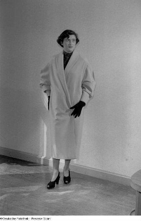 Eine Frau posiert mit Mantel und Handschuhen bei der "Internationalen Messemodenschau", Herbstmesse 1953
