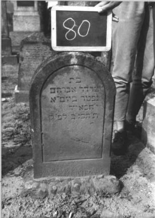 Grabstein 80 (Index: 100114070) Material: Sandstein Zustand: leicht verwittert Maße HxBxT: 86x37x11 cm Beschreibung: Stele, rusticaartiger Sockel, Rundbogenabschluß Besonderheit: Kindergrab: Grabstein 80