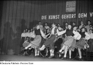 Tanzende Paare, im Hintergrund Chor und Orchester beim Kreisausscheid für Volkskunst