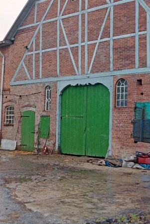 Dorfstraße 6: traufständiges Bauernhaus mit Mansarddach: Giebelseite Wirtschaftstrakt mit Fachwerk, Scheunentor, Stalltür, Luke: davor Hof mit Pflasterung