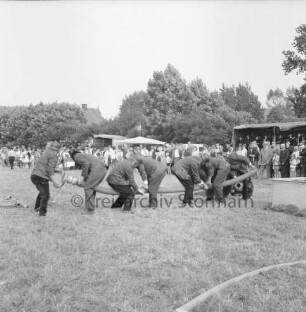 Meddewade: Amtsfeuerwehrfest des Amtes Bad Oldesloe-Land und 80-jähriges Jubiläum der Freiwilligen Feuerwehr Meddewade: Festwiese: Schnelligkeits- und Geschicklichkeitswettbewerb: Feuerwehrteam beim Zusammenkuppeln von Wasserrohrstücken: hinten Zuschauer: 05.07.1969