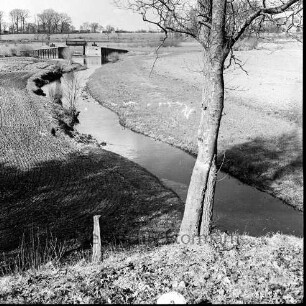 Alster: vorn rechts an Böschung Baum: rechts und links angrenzende Felder: hinten Mitte Sandfelder Schleuse. dahinter Bäume