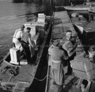 Erste Landung einer britischen Sunderland auf der Havel bei Gatow. Westberliner Bürger transportieren die Kisten ans Ufer