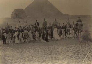 Gizeh, Ägypten. Touristengruppe auf Kamelen und Eseln mit Fremdenführern vor Sphinx und Pyramide von Gizeh