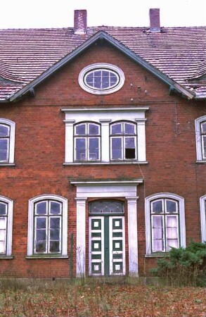 Dorfstraße 32: Bauernhaus aus Backstein: traufständiger Wohntrakt: Straßenfront, Teilansicht: Eingangsportal mit Pilastern und Architrav, Segmentbogen-Sprossenfenster, Frontispiz mit ovalem Fenster